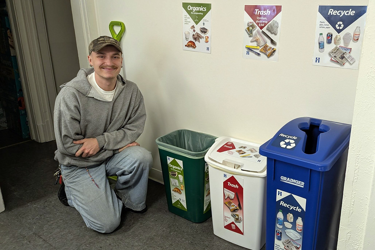 Lowry Hill East Neighborhood Association employee posing with waste bins provided via grants from Hennepin County. 